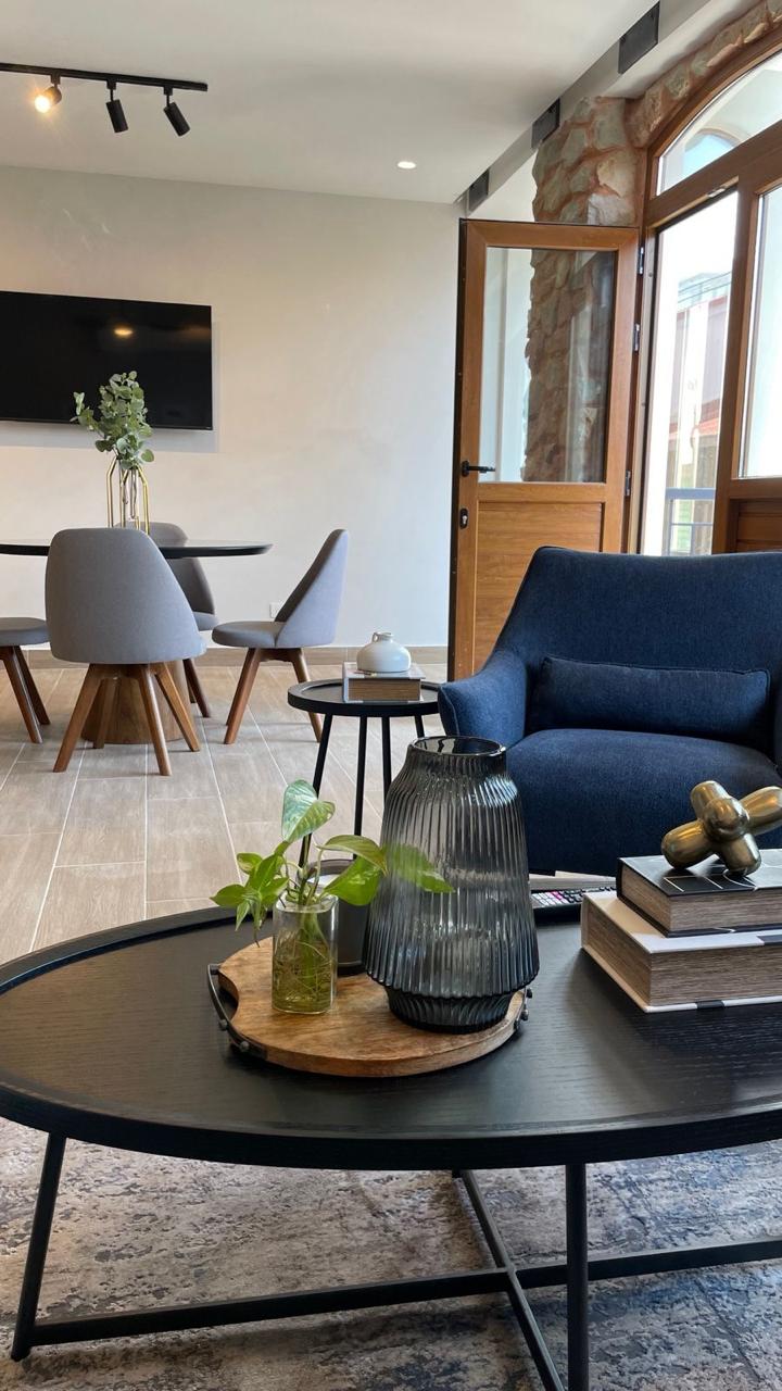 Sala con poltrona azul y puerta de madera hacia el balcón — Airbnb Casco Antiguo