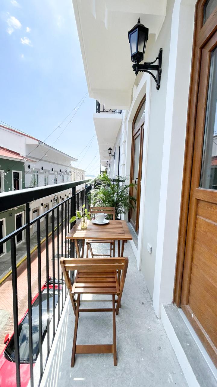 Balcón con mesa y sillas plegables de madera, luces colgantes y vista a la calle del Casco Antiguo — Airbnb Casco Antiguo