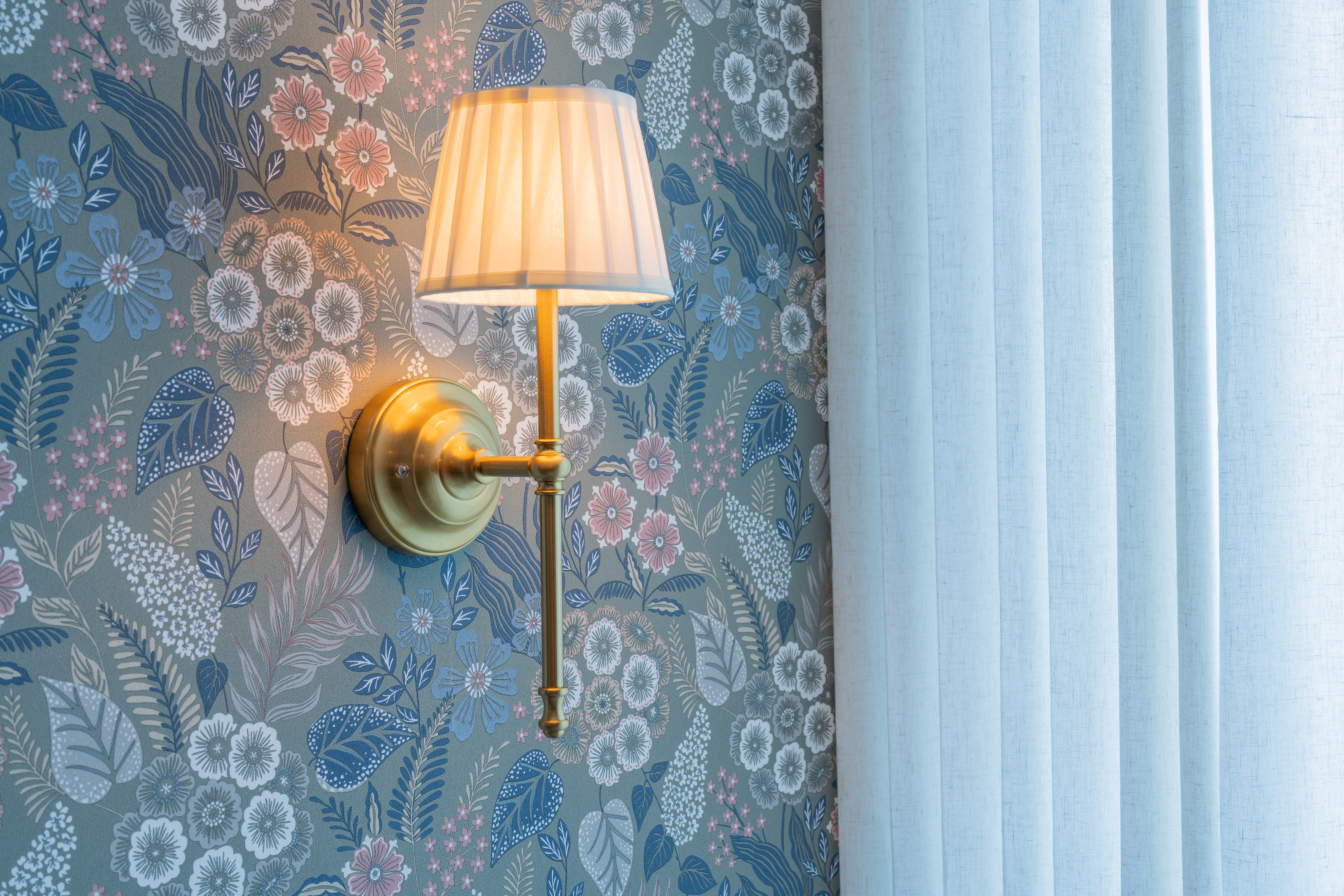 Wall sconce detail against floral wallpaper — Habitación Constanza