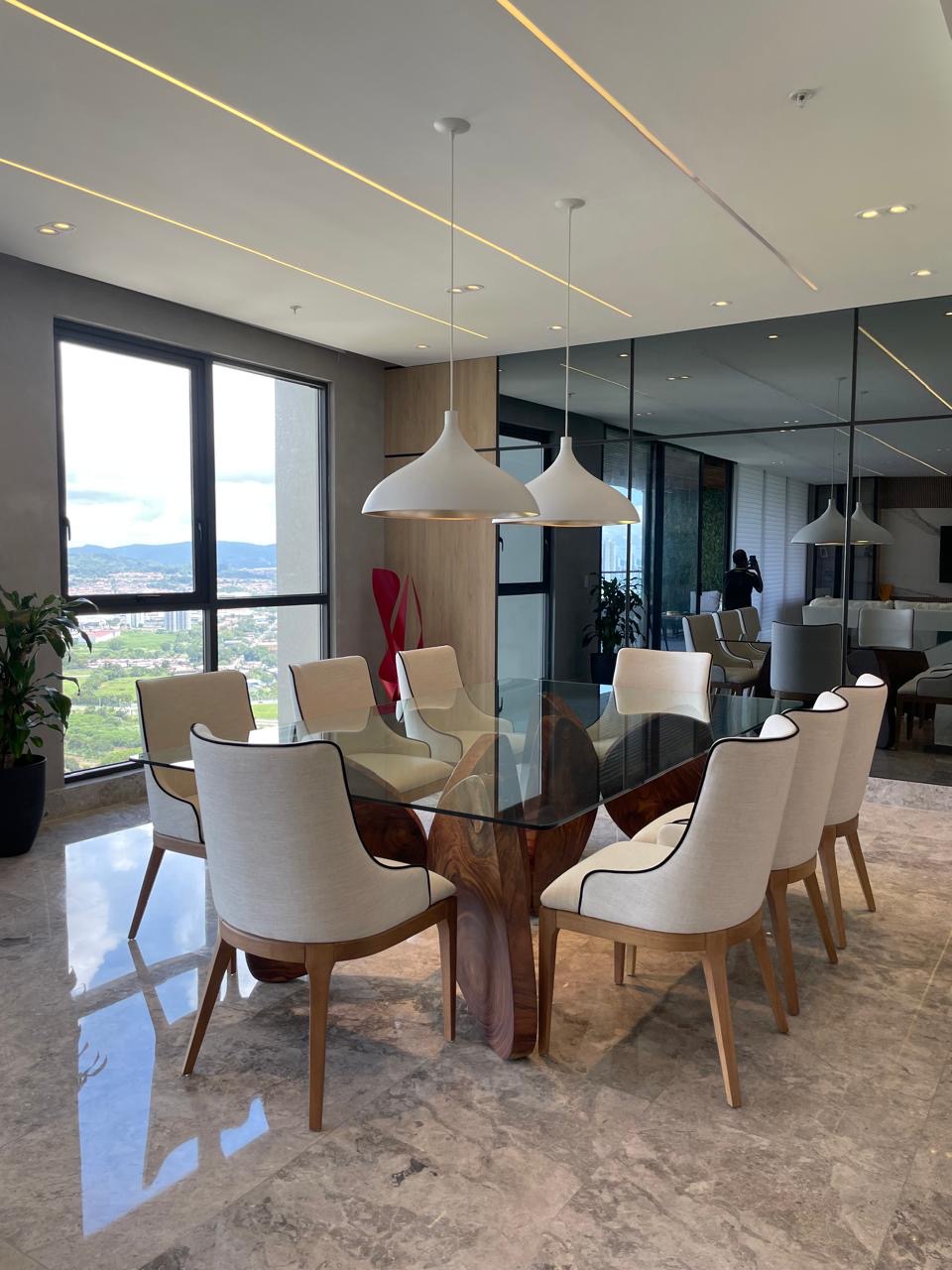 Dining room with glass table on a wood base and city view — PH Empire