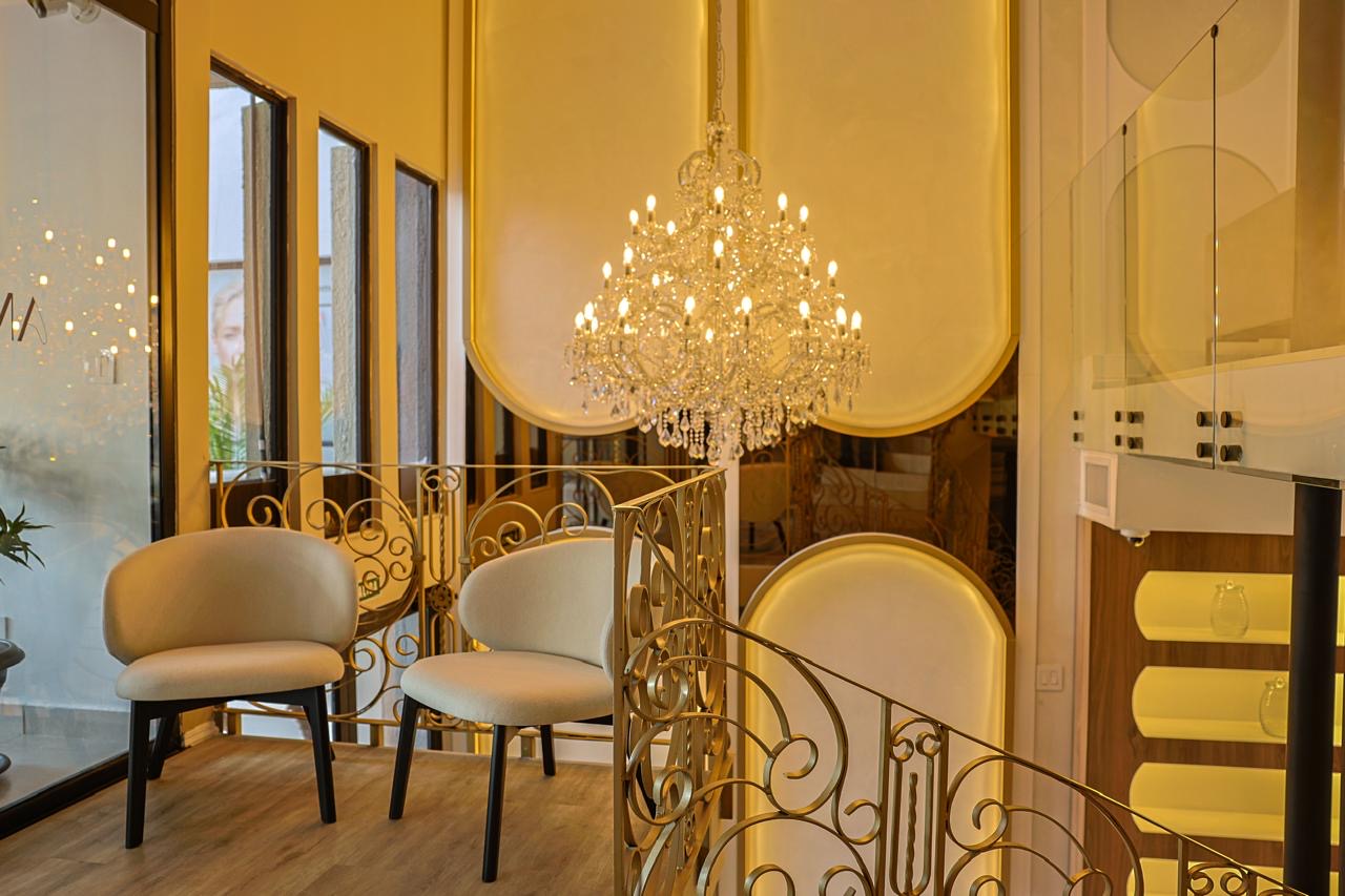 Upstairs lounge with gilded wrought-iron staircase and crystal chandelier — Sonaroma
