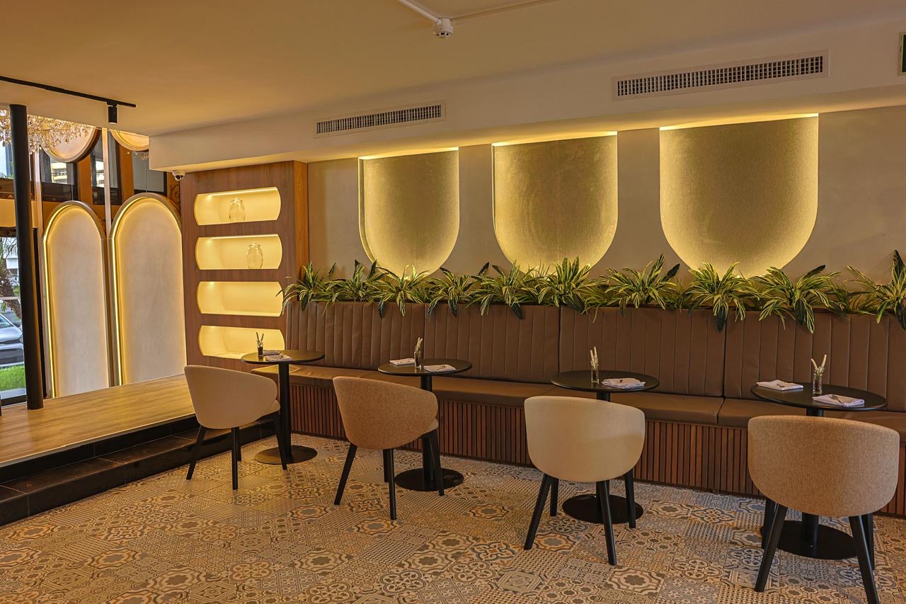 Upholstered banquette under backlit arches with plants — Sonaroma